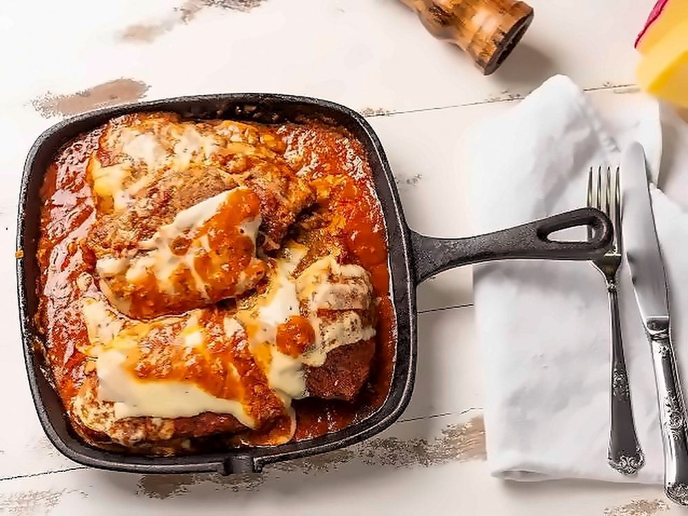 Parmegiana gratinada com molho de tomate na frigideira de ferro, vista de cima