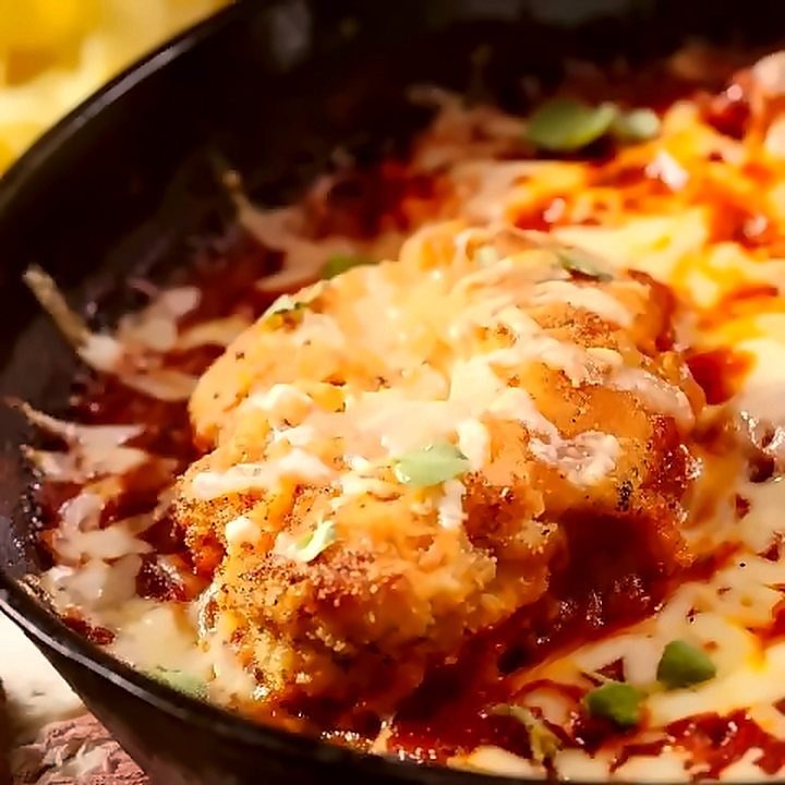 Filé empanado à parmegiana na frigideira de ferro, com queijo derretido