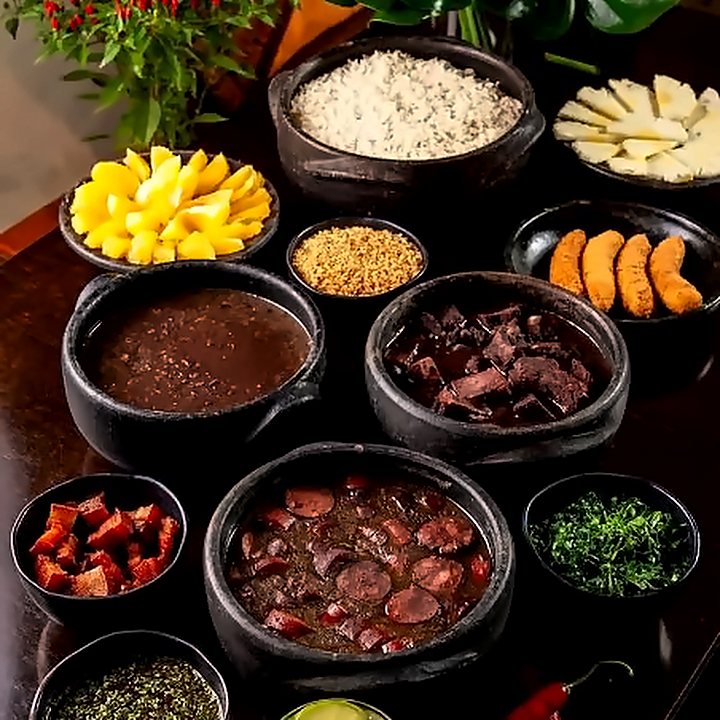 Acompanhamentos da feijoada em potinhos: farofa, vinagrete, couve e pimentas