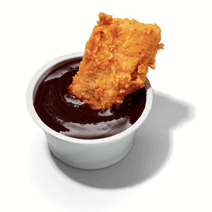 Pote de molho barbecue com um pedaço de frango empanado