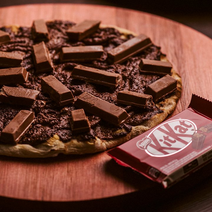 Pizza doce de Nutella com pedaços de KitKat e uma barra de KitKat ao lado