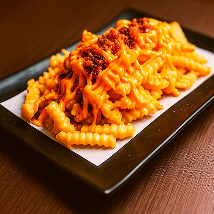Batatas onduladas com cheddar e farofa de bacon no prato preto