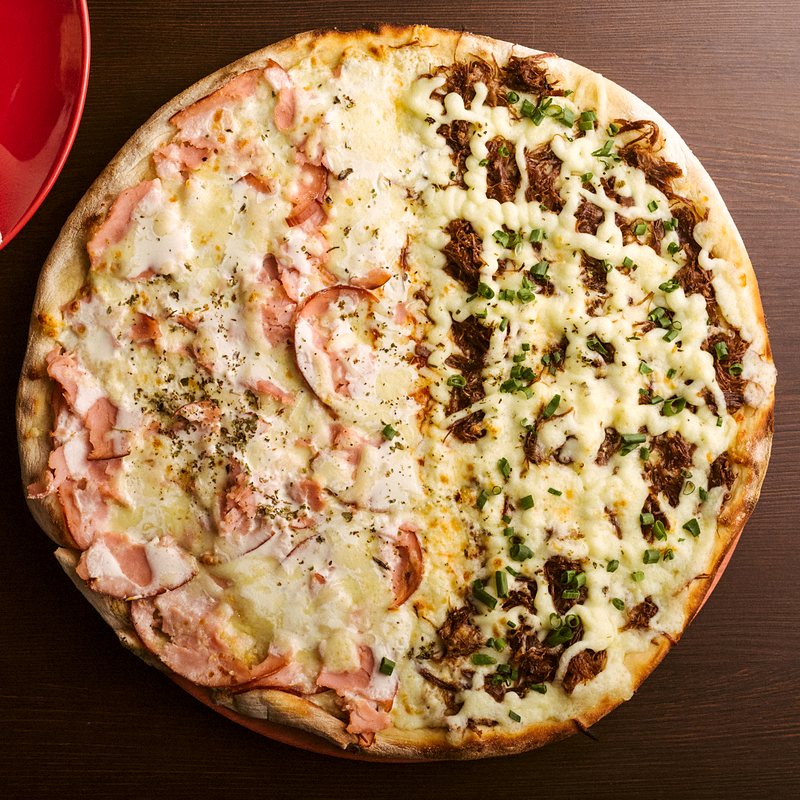 Pizza meio a meio de costela com cebolinha e de presunto, vista de cima